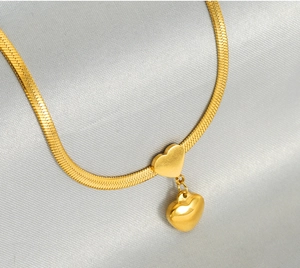 Detail of gold snake chain with double heart pendants showing polished finish and textures