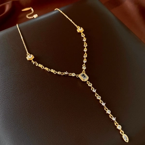 Macro shot of gold-plated Y-necklace with zircon pendants on premium leather background