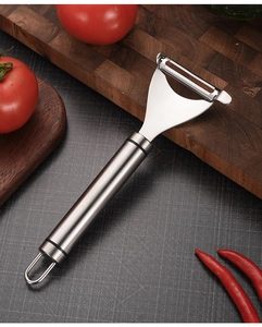 Detail of a 304 stainless steel vegetable peeler with a round handle on a dark cutting mat