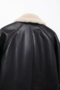 Close-up of black leather jacket back featuring soft cream faux fur collar stitching