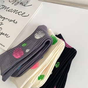 Detailed view of stacked cotton ribbed socks in grey, beige, and black with colorful paint dots