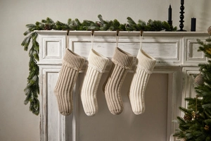 Detail of knitted Christmas stockings with tassels hanging on a fireplace mantel decor