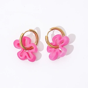 Detail view of pink hollow flower charms on golden hoop earrings with wavy resin petals