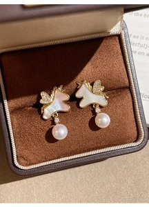 Vue macro de boucles d'oreilles licorne plaquées or avec perles et zircon en boîte