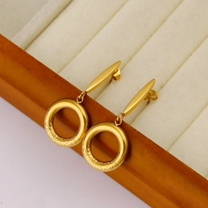 Detailed shot of 18K gold plated bar and circle earrings on a beige velvet jewelry tray