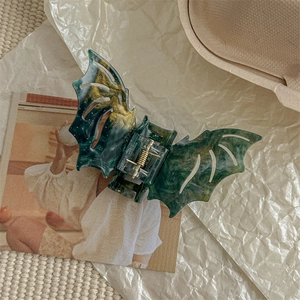 Detailed view of bat wing hair claw clip in dark green and gold glitter marble acetate