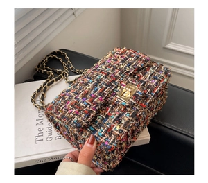 Macro shot of multi-color tweed shoulder bag with gold twist lock and woven texture