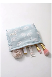 Detail view of jacquard swan pattern makeup bag with cosmetic brushes and toiletries