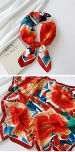 Detailed view of floral silk scarf with red and orange patterns beside an art book