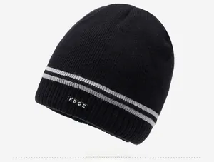 Detail view of black knit beanie with gray stripes and woven FBQE patch on side