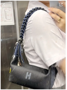 Close-up of dual-color woven rope shoulder strap on a black canvas crossbody bag