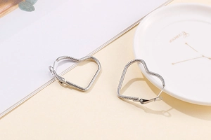 Macro detail of large silver heart-shaped hoop earrings with polished metallic finish