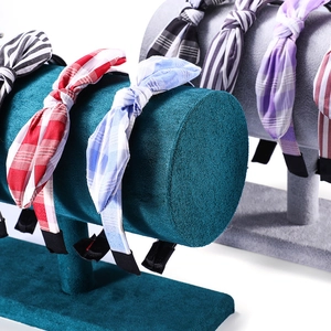Checkered and striped fabric bow headbands displayed on professional velvet stands