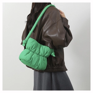 Detail of green quilted nylon puffer bucket bag with knotted shoulder strap on model