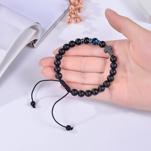 Close-up of 8mm matte black stone beaded bracelet with blue eye bead and cross charm