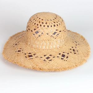 Detail of hollow crochet pattern and frayed tassel edges on natural straw sun hat