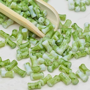 Vue détaillée de perles en marbre vert en forme de bambou versées par une cuillère
