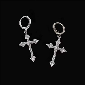 Macro shot of silver cross earrings with inlaid rhinestones on a solid black background