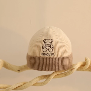 Détail du bonnet tricoté pour bébé avec broderie d'ours et texture en maille côtelée