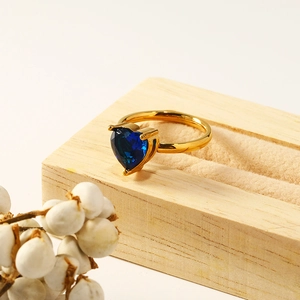 Macro shot of heart-shaped blue zircon ring set in gold metal on a wooden jewelry box