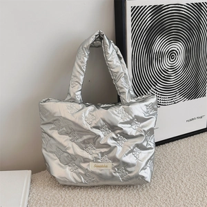 Dettaglio della borsa tote argento metallizzato con trama trapuntata a fiocco e logo