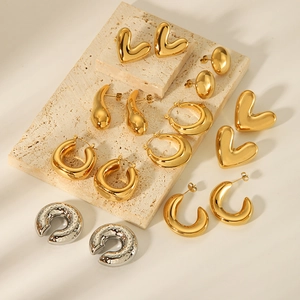 Minimalist 18K gold and silver heart stud earrings and C-shaped hoops on marble blocks