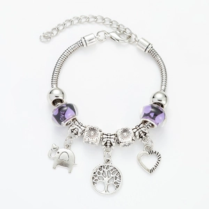 Detailed view of silver charm bracelet with purple glass beads, elephant and tree of life
