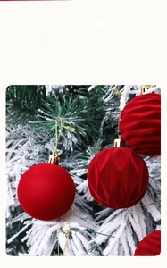 Close-up of red flocked Christmas ornaments with geometric textures on snowy pine branches