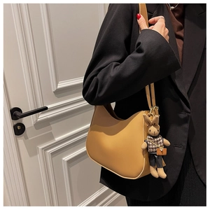 Detail of yellow leather shoulder bag featuring a cute rabbit charm on a black blazer
