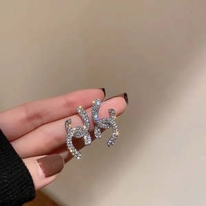 Macro shot of silver stud earrings with interlocking C shape and micro-inlaid crystals