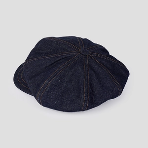 Détail d'une casquette gavroche en jean bleu foncé avec coutures contrastées et huit pans