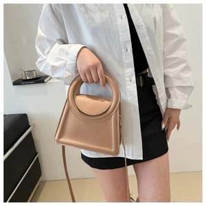 Detail of minimalist beige handbag with unique circular handle and elegant stitching
