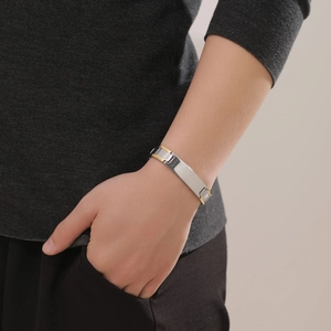 Macro view of two-tone stainless steel bracelet with a smooth rectangular plaque on wrist