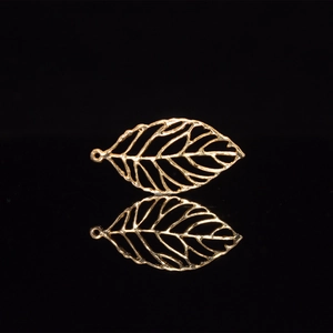 Macro shot of a gold hollow leaf charm with ring on a black reflective surface