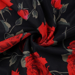 Dettaglio dell'abito a fiori con volant in rete con stampa a rose rosse e trama a maglia