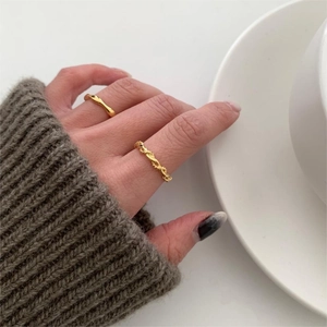 Close-up of stacked 925 sterling silver twist and minimalist wave rings in gold finish