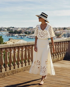 Detail of white two-piece resort set featuring intricate floral laser cut-out patterns