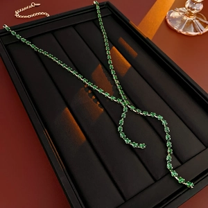 Elegant gold Y-shaped necklace with green zircon waterdrop pendant on black display tray