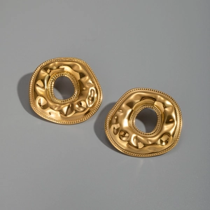 Macro detail of golden irregular donut earrings with textured wavy surface and bead edges