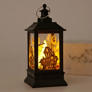 Close-up of black Halloween lantern with haunted house silhouette and warm LED light