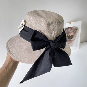 Dettaglio del cappello da sole in lino con grande fiocco di seta nera e etichetta UV