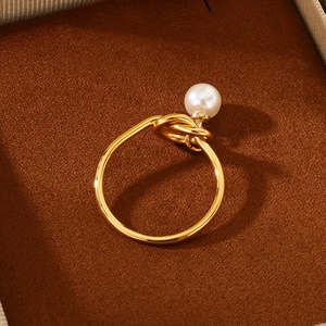 Close-up of golden pearl knot ring placed elegantly inside a brown velvet jewelry box