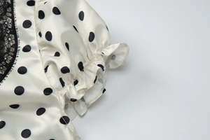 Dettaglio della manica dell'abito bianco a pois con pizzo nero e bordi a volant