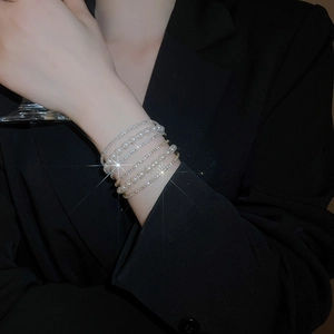 Close-up of multilayer silver bracelet with sparkling crystals and pearls on model