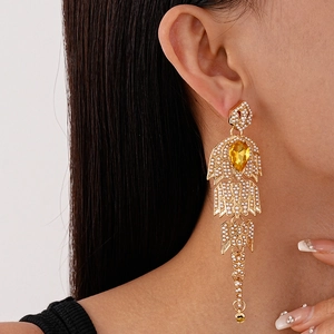 Detail of vintage gold tassel earrings with imitation pearls and yellow teardrop gem