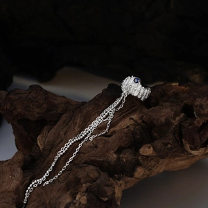 Detailed macro view of S925 silver ear cuff with blue gemstone and hanging tassel chains