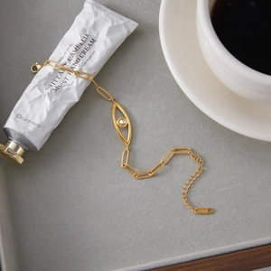 Detailed view of 18K gold plated stainless steel evil eye bracelet on a grey display tray