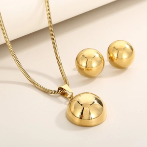 Detail of golden stainless steel jewelry set featuring a dome pendant and stud earrings