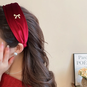 Close-up of elegant burgundy velvet headband with a tiny golden metal bow detail