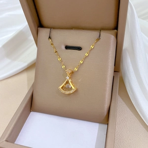 Close-up of a gold skirt-shaped pendant with diamonds in a beige jewelry box